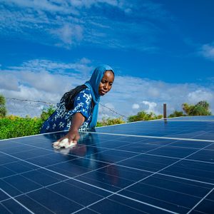Solar wells to address the problem of drought, a woman cleaning a solar energy panel Solar wells to address the problem of drought, a woman cleaning a solar energy panel